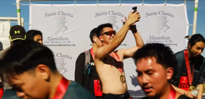 A runner at the Santa Clarita Marathon taking a picture of himself with his medal after the race